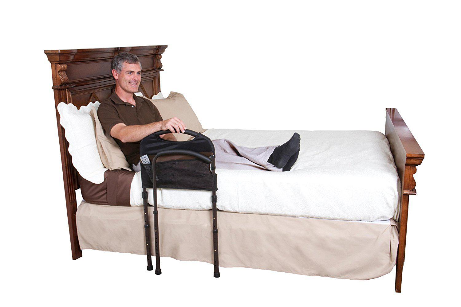 Man sitting in a bed holding onto a Stander Mobility Bed Rail